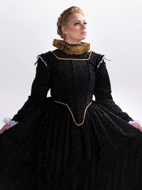 Woman wearing an Elizabethan-style black dress with gold trim and a ruff collar